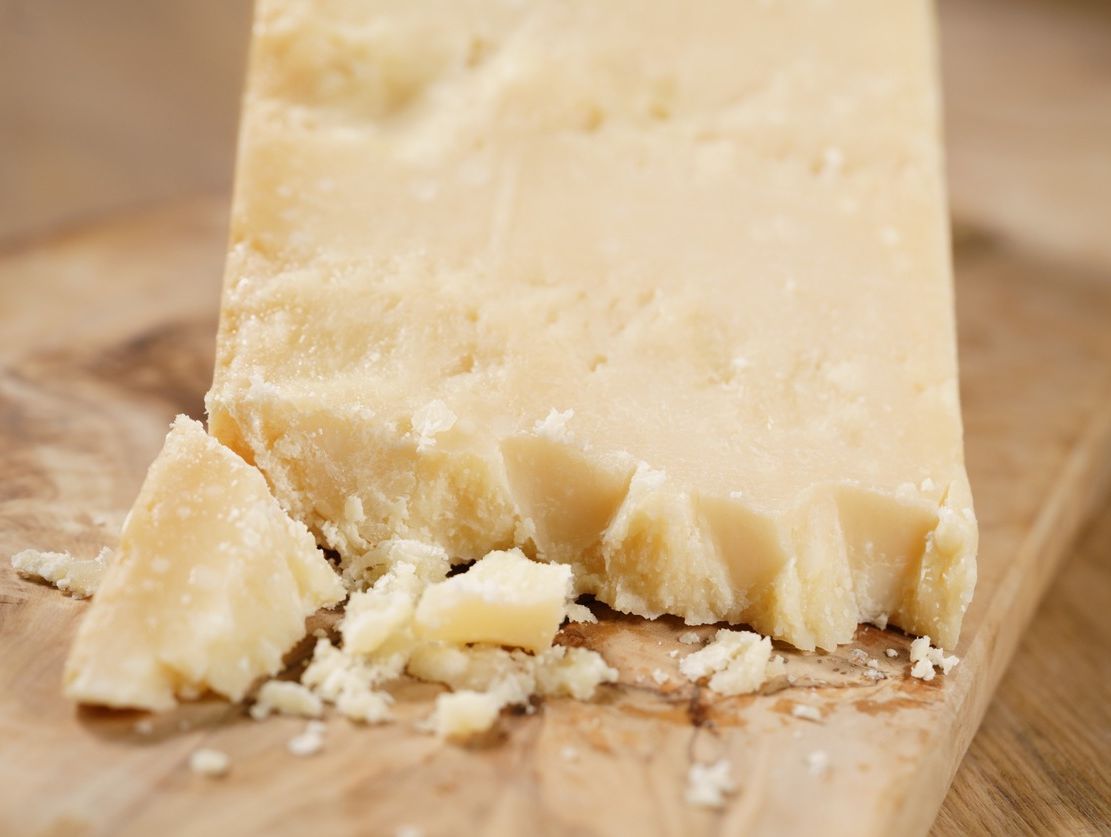cuña de queso muy curado en una tabla de cortar